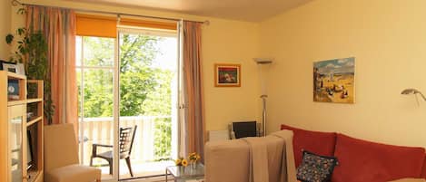 Das Wohnzimmer mit Sitzgarnitur und Zugang zum Balkon