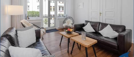 Wohnbereich mit Couch, TV und Blick zum Balkon