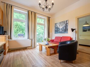 Der Wohnbereich mit Couchgarnitur und Küchenzeile sowie einem Zugang zum möblierten Balkon