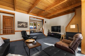 Sunken living room area with ample seating and flat screen TV.