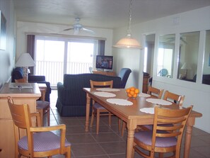 Dining area with living room and balcony overlooking the beach in background