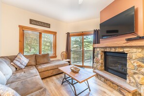 Spacious living area featuring large couch, flat screen TV, and gas fireplace.