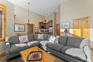 Open concept living area with ample sunlight, queen sleeper sofa, TV, and fireplace.