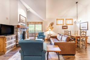 Living area featuring flat screen TV, gas fireplace, vaulted ceiling, access to the private balcony and cozy furniture.