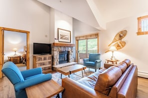 Living area featuring flat screen TV, gas fireplace, vaulted ceiling, access to the private balcony and cozy furniture.