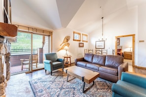Living area featuring flat screen TV, gas fireplace, vaulted ceiling, access to the private balcony and cozy furniture.