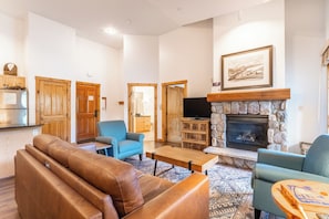 Living area featuring flat screen TV, gas fireplace, vaulted ceiling, access to the private balcony and cozy furniture.