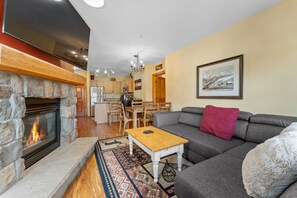 Living area offering cozy furniture, gas fireplace, mounted TV and access to the private balcony.
