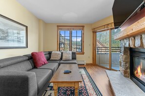 Living area offering cozy furniture, gas fireplace, mounted TV and access to the private balcony.