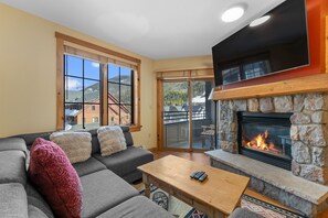 Living area offering cozy furniture, gas fireplace, mounted TV and access to the private balcony.
