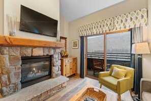 Living area with queen sleeper sofa, fireplace, and balcony access.