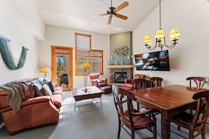 Living area features ample seating, flat screen TV, fireplace, and deck access.