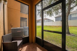 Screened porch with cozy seating overlooking a grassy outdoor area.