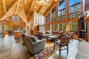 Main living area featuring floor to ceiling windows, incredible light, vaulted ceiling, oversized gas fireplace, ample seating, main balcony access, and a flat screen TV.