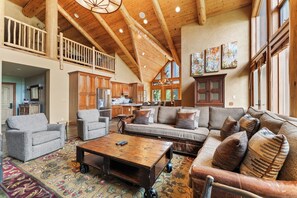 Main living area featuring floor to ceiling windows, incredible light, vaulted ceiling, oversized gas fireplace, ample seating, main balcony access, and a flat screen TV.