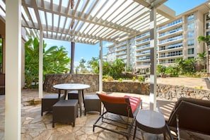 Relax in this stylish pergola-covered patio with cushioned lounge chairs and tropical resort surroundings HKK-113