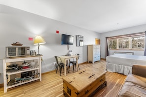 Living area with sleeper sofa, mounted flat screen TV and hardwood flooring.