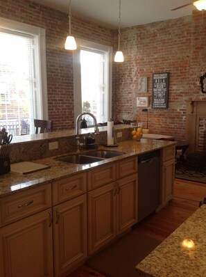 Kitchen view to living room with large floor to ceiling windows that go outside