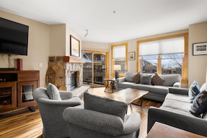 The living area featuring a queen-sized sleeper sofa, flat screen TV, gas fireplace and access to the private balcony.