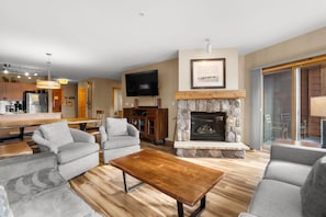 The living area featuring a queen-sized sleeper sofa, flat screen TV, gas fireplace and access to the private balcony.