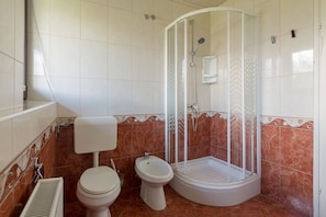 A modern bathroom with a glass shower stall, washbasin, toilet and bidet.