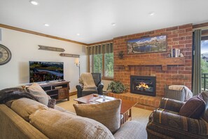 The living room of this Steamboat vacation rental, with couch, armchair, TV, and fireplace.