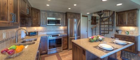 Kitchen with a set center island, countertop sink, and refrigerator and oven range.