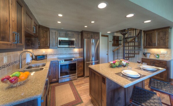 Kitchen with a set center island, countertop sink, and refrigerator and oven range.