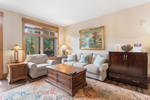 Living room featuring a stone fireplace, mounted TV, queen sleeper sofa, and 2 twin XL Murphy beds