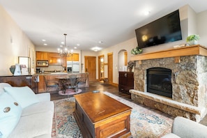 Living room featuring a stone fireplace, mounted TV, queen sleeper sofa, and 2 twin XL Murphy beds
