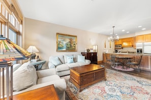 Living room featuring a stone fireplace, mounted TV, queen sleeper sofa, and 2 twin XL Murphy beds