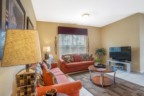 The living room offers a cozy retreat amidst modern furnishings and warm ambiance, inviting guests to unwind and create cherished memories.