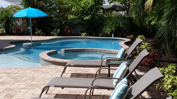 Heated pool with swim up seating area with umbrealla and spa. Multiple lounge chairs