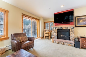 Living area with mounted TV, gas fireplace and sleeper sofa.