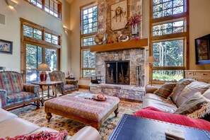 Grand living room with wood burning fireplace and stunning window walls for unbeatable natural light