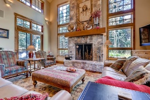 Grand living room with wood burning fireplace and stunning window walls for unbeatable natural light