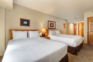 One of the bedrooms offer two queen beds with wooden furniture.