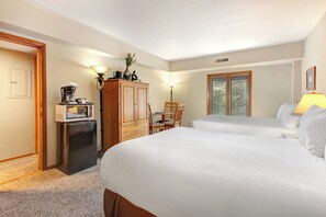 One of the bedrooms offer two queen beds with wooden furniture.