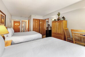 One of the bedrooms offer two queen beds with wooden furniture.