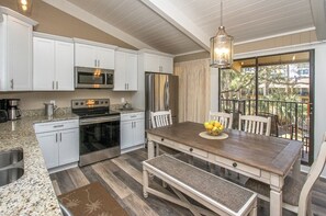 Kitchen and Dining Area - The kitchen features all new wood cabinetry, granite counters, stainless appliances and wood grain tile flooring.  You enjoy a view of the courtyard and pool through the sliding doors to the balcony.