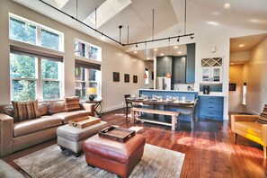 Living room with leather ottomans, yellow leather accent chair and hardwood floors with light area rug