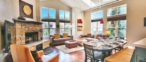 Bright open living room and dining room, abundant windows, stone fireplace and wall mounted large screen TV