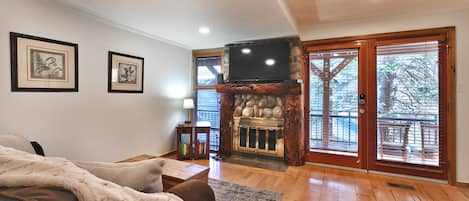 Open living area with hardwood floors, gas fireplace and mantle mounted TV