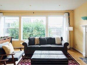 Spacious living room has expansive windows opening towards the water view