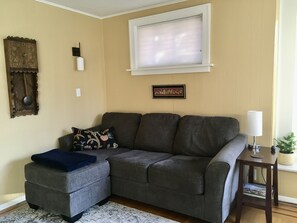 Light filled newly painted living room has ceiling fan and bay windows.