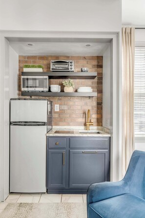 A well appointed kitchenette featuring a fridge, toaster oven, microwave, and an induction cooktop. 