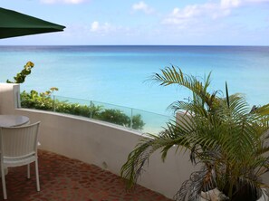 Private terrace with covered dining table and 4 lounge chairs overlooking ocean