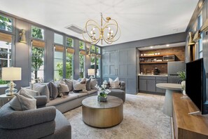 The space is illuminated by a statement chandelier and natural light streaming through large windows.