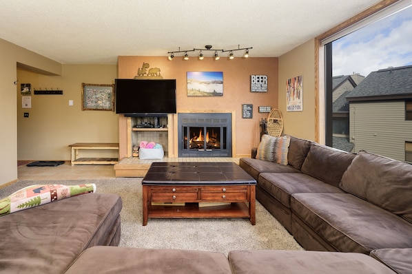 The living room features a sectional sleeper sofa, a fireplace and large windows