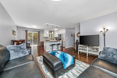 Living Room features 1 (of 2) 50+" Smart TVs, opens to kitchen & island.